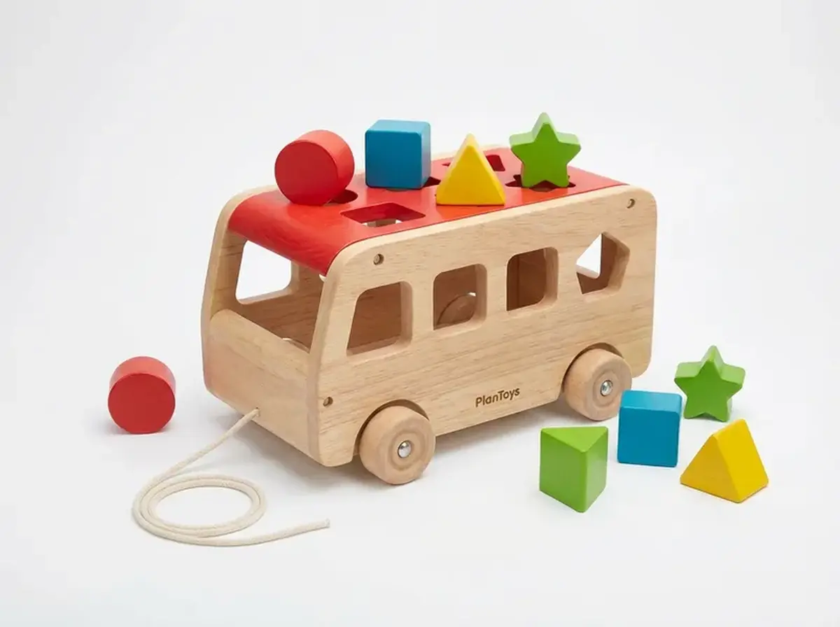 PlanToys-style wooden sorting bus used for shape matching, pretend play, and early classification